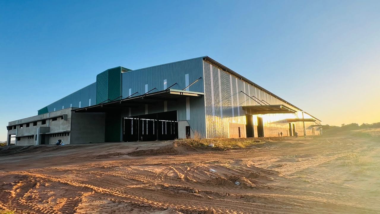 Completed cladding and canopies along the Gabane warehouse elevation at sunset